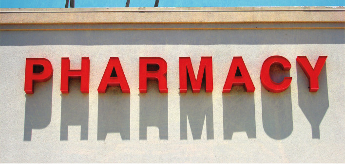 Pharmacy sign with sky and palm trees behind