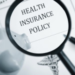 A maginfying glass looking at the words "Health Insurance Policy"