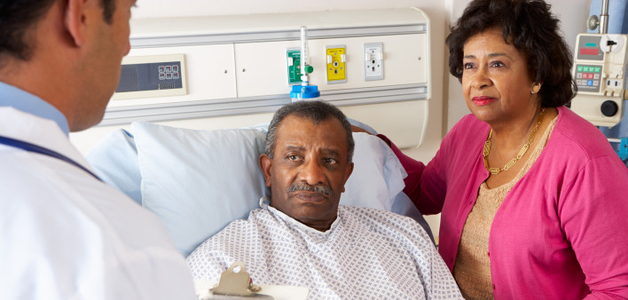 Doctor Talking To Senior Couple On Ward Worried