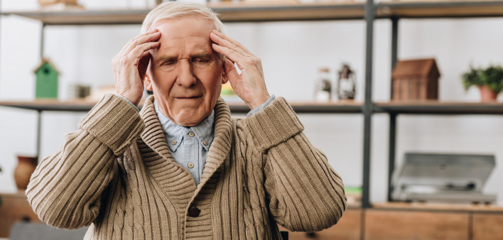 Pensioner having headache while sitting near wooden toys