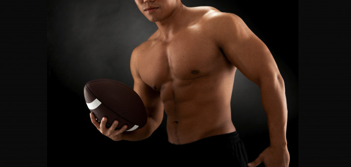 shirtless man holding football