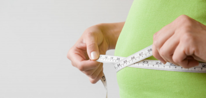 Fat overweight woman measuring her waist.