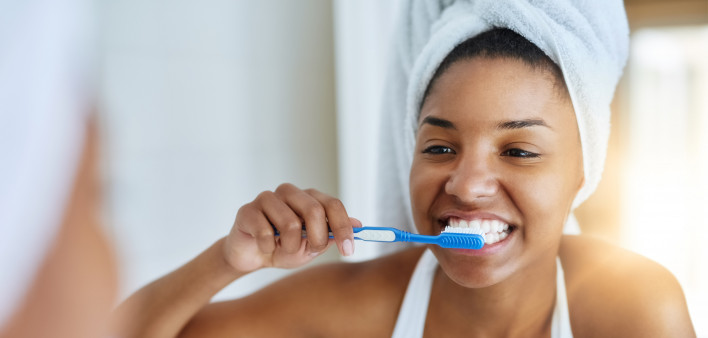 Shot of an attractive young woman brushing her teeth in the bathroom at home