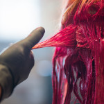 Young woman getting her hair dyed a vivid red in salon