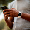 African-American male with smart watch and headphones texting messages on mobile phone during jogging session.