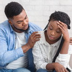 Loving husband supporting his depressed wife during psychotherapy session with counselor
