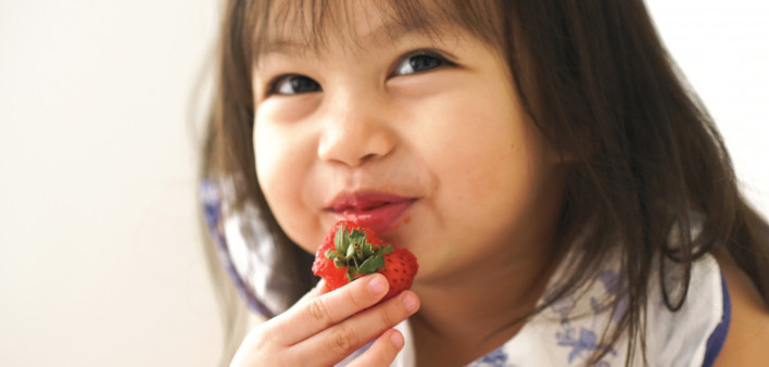 small girl child eating strawberry and smiling