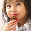 small girl child eating strawberry and smiling