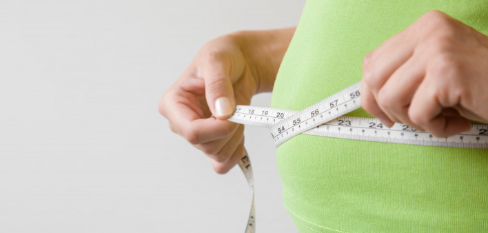 Fat overweight woman measuring her waist.