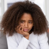Close up focus african american adolescent girl feels badly melancholic sad and frustrated. On background angry mother accusing scolding reprimanding teen daughter. Teenager behavior problems concept