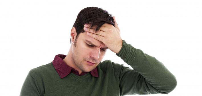 Young man holding his hand to his forehead and holding a thermometer