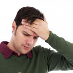 Young man holding his hand to his forehead and holding a thermometer