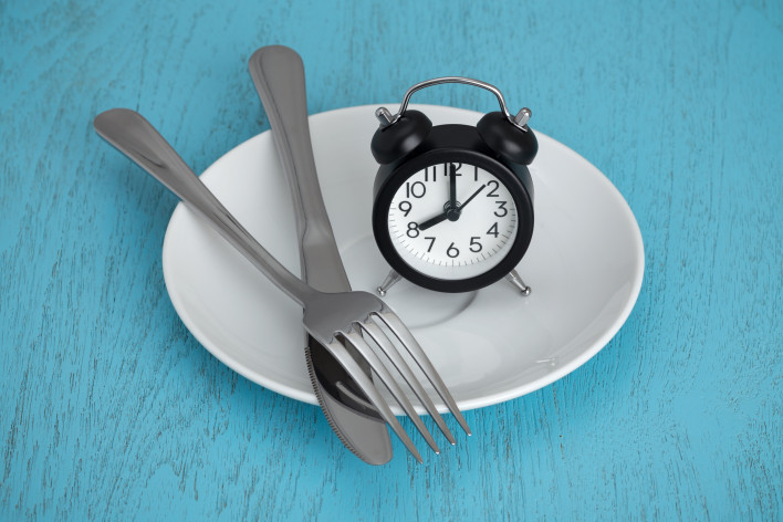alarm clock on plate with fork and knife fastting diet