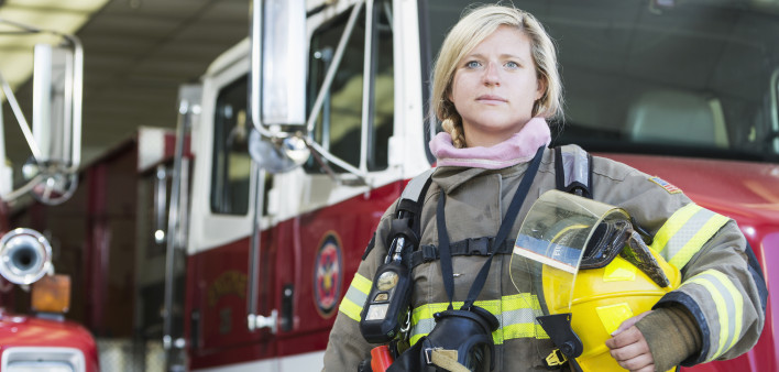 Female firefighter standing in front of fire truck