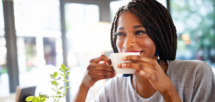 Beautiful young african woman enjoying a cup of coffee in coffee shop