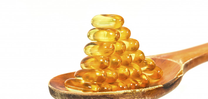 Vitamin D Capsules on wooden spoon