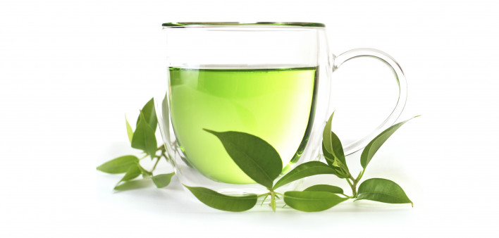 a cup of green tea and fresh tea leaves