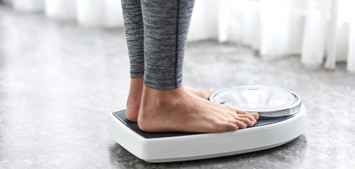 Young healthy girl on home scales
