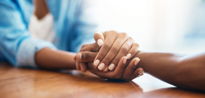 Closeup shot of two unrecognizable people holding hands in comfort at home