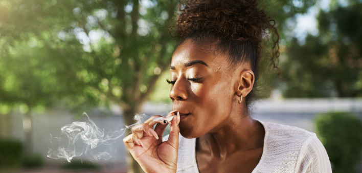 happy african american woman smoking marijuana joint in back yard