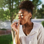 happy african american woman smoking marijuana joint in back yard