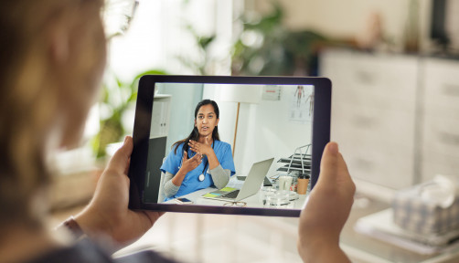 Over the shoulder shot of a patient talking to a doctor using of a digital tablet