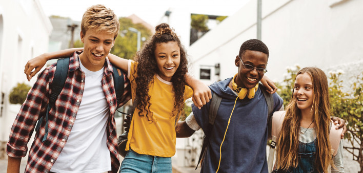 group of young kids walking arm and arm laughting