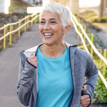 Portrait of elderly woman running in the park in early morning. Photo of Attractive looking gray hair mature woman keeping fit and healthy. Fit mature woman jogging on the pier on a sunny day while.