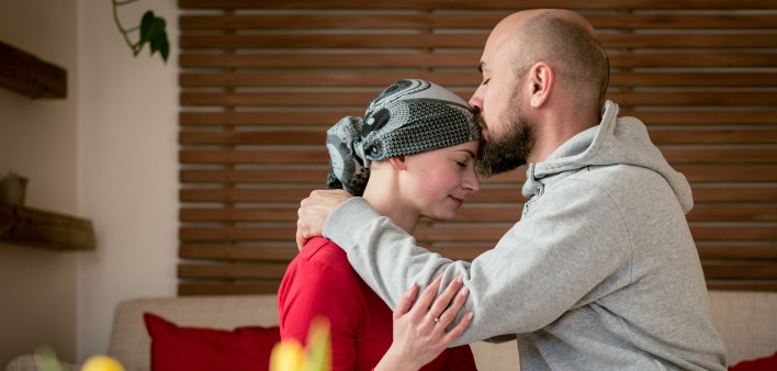 Supportive husband kissing his wife, cancer patient, after treatment in hospital.