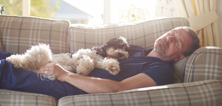 man sleeping on couch with his dog