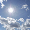 bright sun shining in blue sky with white clouds