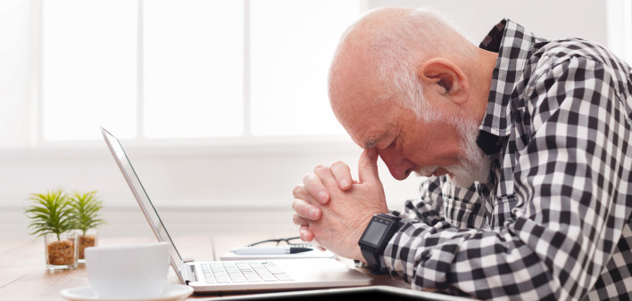 Worried senior man using laptop at home.
