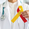 World hepatitis day and HIV/ HCV co-infection awareness with red yellow ribbon in medical doctor hand