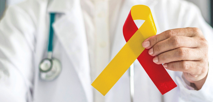 World hepatitis day and HIV/ HCV co-infection awareness with red yellow ribbon in medical doctor hand