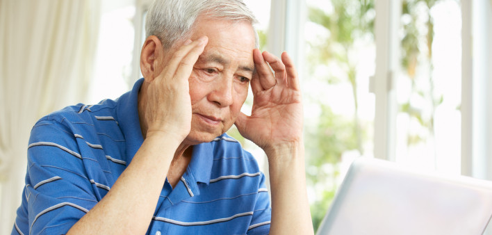 Worried Senior Chinese Man Sitting At Desk Using Laptop At Home