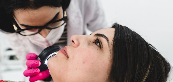 Examining the patient's skin with a dermatological lens