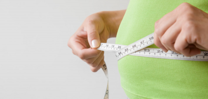 Fat overweight woman measuring her waist.