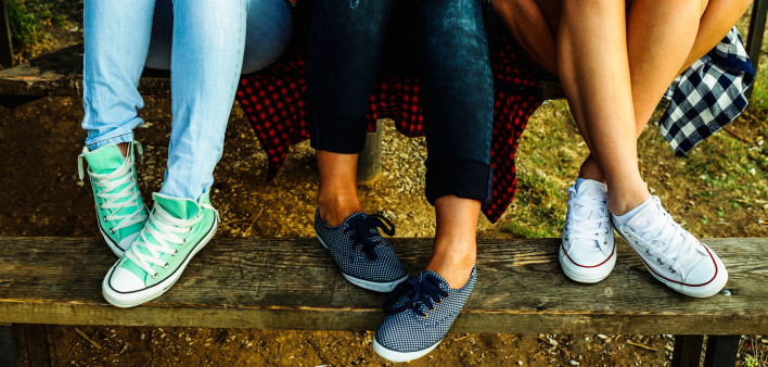Female feet in jeans and sports shoes on a bench