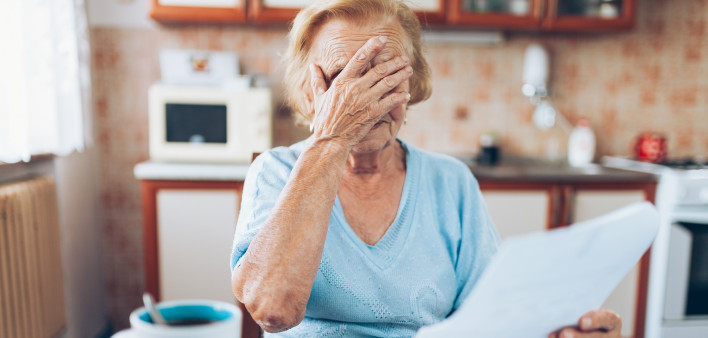 Elderly woman looking at her utility bills and paperwork
