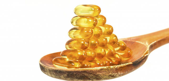 Vitamin D Capsules on wooden spoon