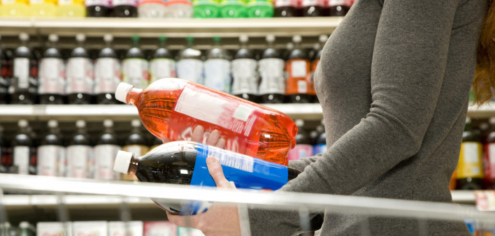 Woman comparing ingredients on soda bottle