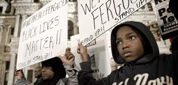 A young protester and his mother are seen holding signs at Dillworth Park at Philadelphia City Hall.