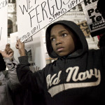 A young protester and his mother are seen holding signs at Dillworth Park at Philadelphia City Hall.