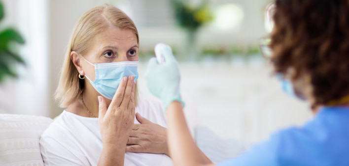 Doctor examining sick patient in face mask. Ill woman in health clinic for test and screening. Home treatment of virus.