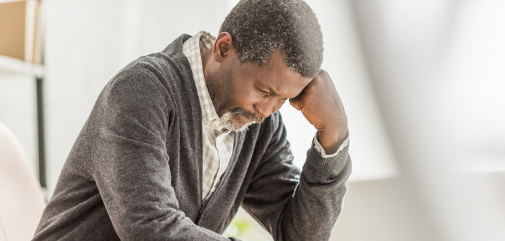 Selective focus of depressed african american man sitting with bowed head