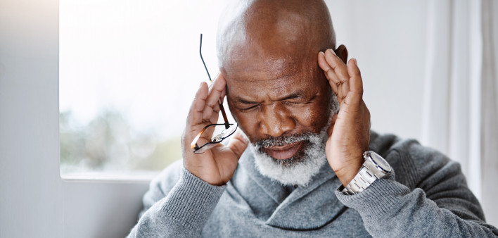 Shot of a handsome senior man suffering with a headache at home