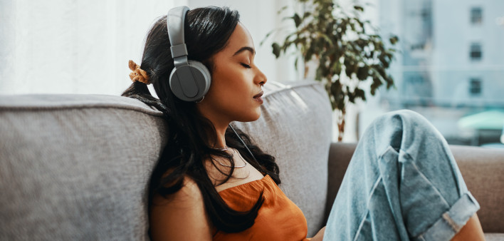 Shot of a young woman using headphones while relaxing on the sofa at home