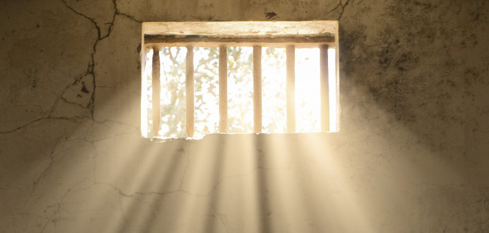 light shining through bars of prison window 