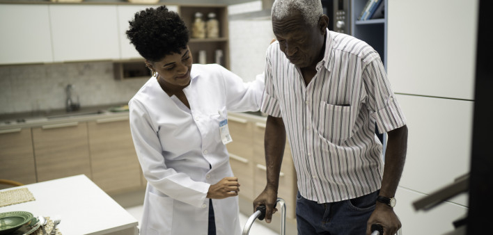 Caretaker assisting senior man with walker