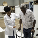 Caretaker assisting senior man with walker